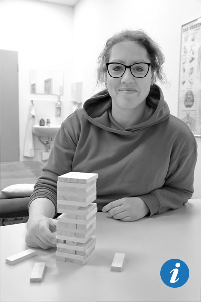 Eine junge Frau sitzt, vor ihr ein Turm aus Bauklötzen.